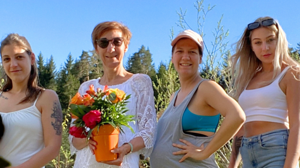 Mama mit einem Blumenstrauß, Katrin, Mara und Anna stehen vor einem Zaun auf einer Wiese