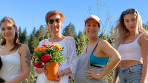 Mama mit einem Blumenstrauß, Katrin, Mara und Anna stehen vor einem Zaun auf einer Wiese