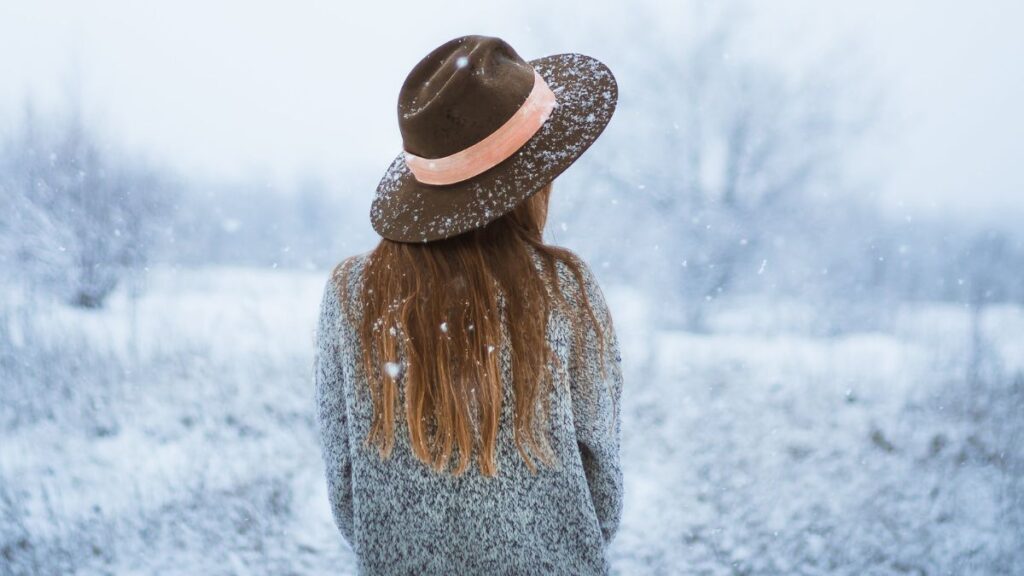 Eine Frau die den Rücken zeigt und alleine im Schnee steht
