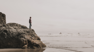 Mann steht mutig auf einem Stein vor dem großen weitem Meer